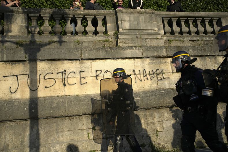 Policías patrullando junto a un graffiti que dice Justicia para Nahel mientras varios jóvenes se reúnen en la Plaza de la Concordia durante una protesta en París, Francia, el viernes 30 de junio de 2023. (AP Foto/Lewis Joly, Archivo)
