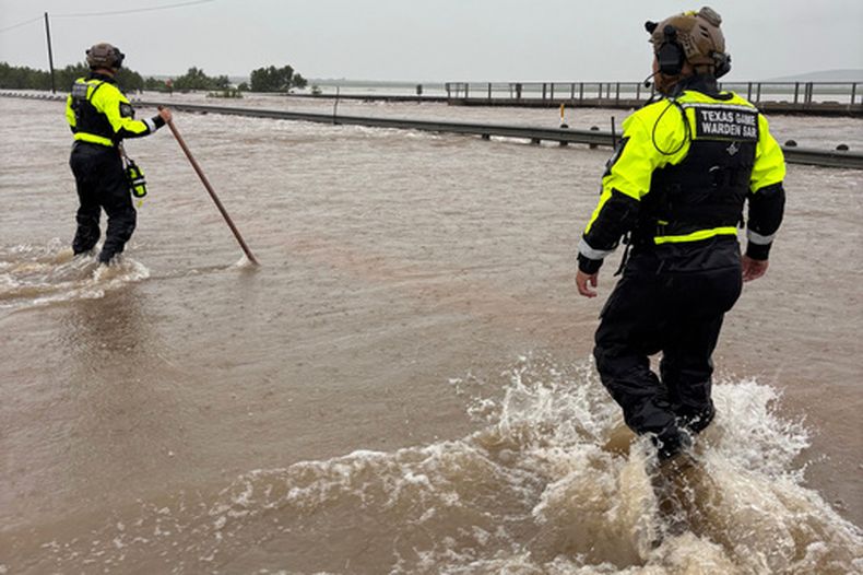 En la imagen, proporcionada por el Departamento de Parques y Vida Silvestre de Texas, guardias de coto caminan a través de las aguas dejadas por las fuertes lluvias en el condado de Uvalde, Texas, el martes 14 de julio de 2026. (Departamento de Parques y Vida Silvestre de Texas vía AP)