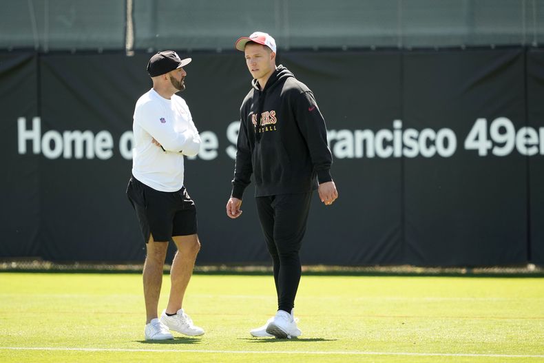 El corredor de los 49ers de San Francisco, Christian McCaffrey, a la derecha, observa ejercicios durante la práctica de fútbol americano de la NFL en Santa Clara, California, el martes 4 de junio de 2024. (AP Foto/Tony Avelar)