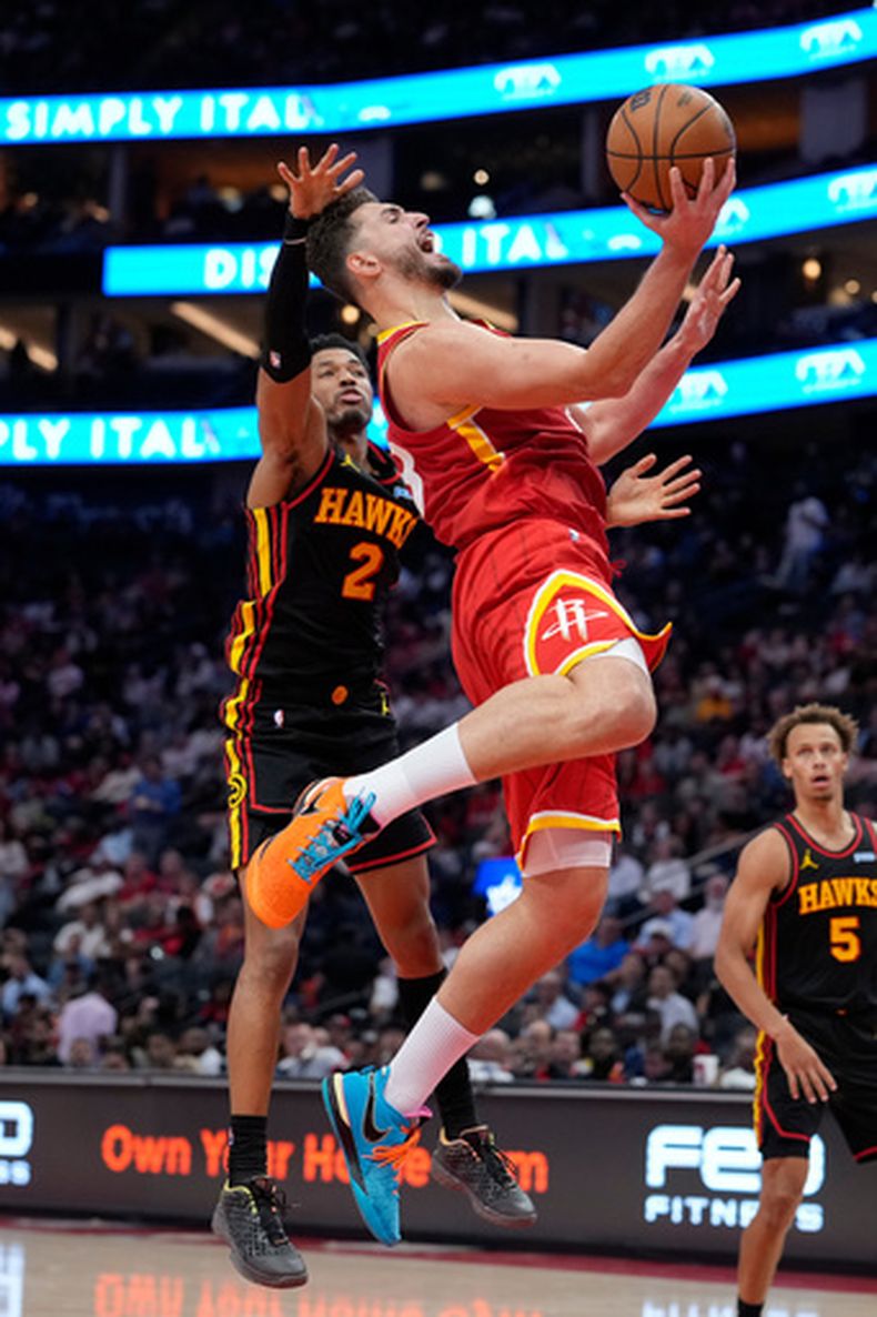 Alperen Sengun, con el balón, de los Rockets de Houston, recibe una falta de Aaron Wiggins (2), de los Hawks de Atlanta, durante el tercer cuarto del juego de baloncesto de la NBA, el lunes 26 de octubre de 2026, en Houston. (AP Foto/Kevin M. Cox)