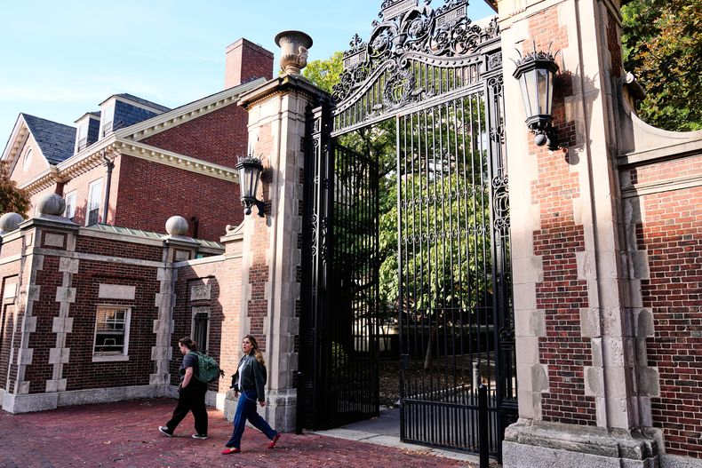 Dos mujeres atraviesan una puerta en el jardín Harvard de la universidad del mismo nombre, el martes 30 de septiembre de 2025, en Cambridge, Massachusetts. (AP Photo/Charles Krupa)