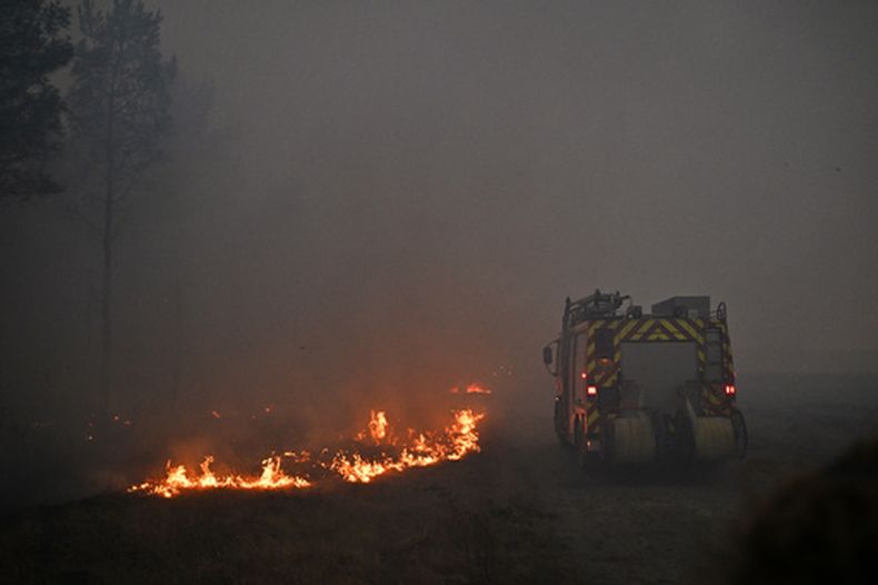 Un camión de bomberos avanza entre el humo de un incendio cerca de Marcheprime, a las afueras de Burdeos, Francia, el domingo 26 de julio de 2026. (AP Foto/Emma Da Silva)