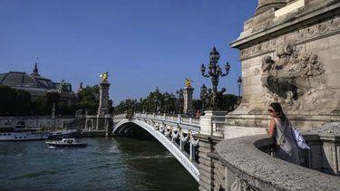 Una mujer descansa en el puente Alexandre III sobre el río Sena de París, el jueves 1 de junio de 2023. (AP Foto/Michel Euler)