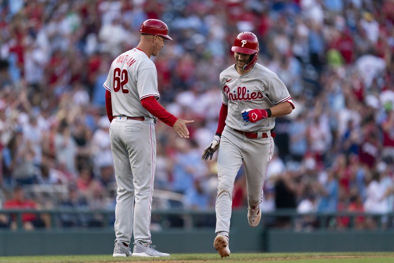 Trea Turner, de los Filis de Filadelfia, festeja con el coach de tercera Dusty Wathan, luego de batear su segundo jonrón en el juego ante los Nacionales de Washington, el sábado 19 de agosto de 2023 (AP Foto/Stephanie Scarbrough)