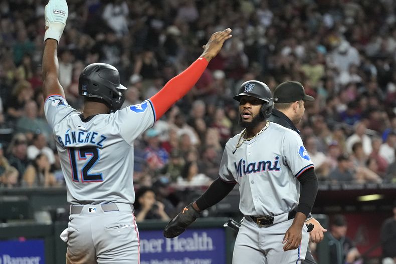 Jesús Sánchez (12) y Bryan De La Cruz, de los Marlins de Miami, celebran después de anotar en contra de los Diamondbacks de Arizona duriante la séptima entrada del juego de béisbol del domingo 26 de mayo de 2024, en Phoenix. (AP Foto/Ross D. Franklin)