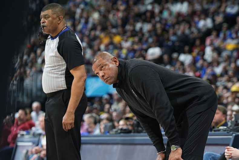 Doc Rivers, derecha, coach de los Bucks de Milwaukee, observa las acciones en la duela al lado del árbitro Tony Brothers en la segunda mitad del juego de baloncesto de la NBA en contra de los Nuggets de Denver, el lunes 29 de enero de 2024, en Denver. (AP Foto/David Zalubowski)
