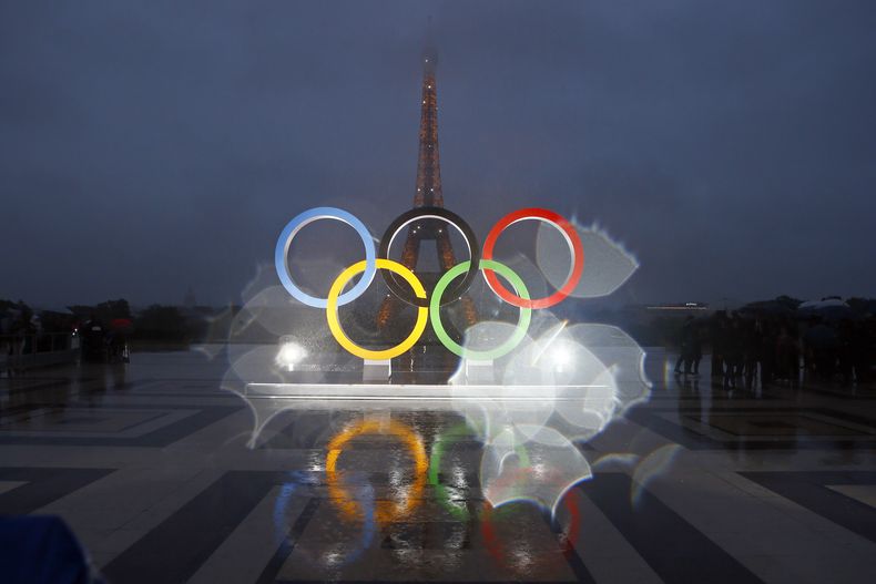 ARCHIVO - Esta foto que fue tomada con una lente con gotas de lluvia muestra los anillos olímpicos en la plaza Trocadero que observa la Torre Eiffel, luego de una votación en Lima, Perú, otorgando los Juegos de 2024 a la capital de Francia, París, el 13 de septiembre de 2017. (AP Foto/Francois Mori, Archivo)