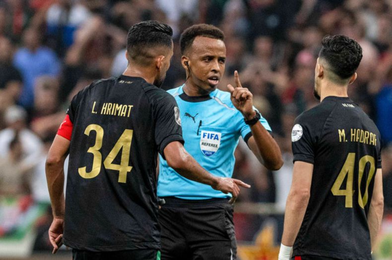 El árbitro somalí Omar Artan, en el centro, habla con jugadores tras pitar un penalti en el partido de la Liga de Campeones CAF entre el AS FAR Rabat y Mamelodi Sundowns, en Rabat, Marruecos, el domingo 24 de mayo de 2026. (AP Foto/Mosaab Elshamy)