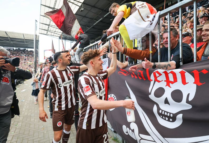ARCHIVO - Foto del 17 de mayo del 2025, Philipp Treu y Manolis Saliakas del St. Pauli saludan a los aficionados en el encuentro de la Bundesliga ante el Bochum. (Christian Charisius/dpa via AP, Archivo)
