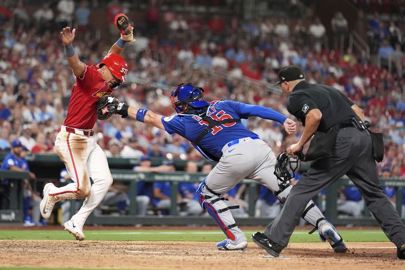 Masyn Winn, izquierda, de los Cardenales de San Luis, es retirado en el plato por el receptor de los Cachorros de Chicago Carson Kelly mientras el umpire principal Roberto Ortiz, derecha, se prepara para hacer la llamada durante la octava entrada del juego de béisbol de Grandes Ligas, el viernes 8 de agosto de 2025, en San Luis. (AP Foto/Jeff Roberson)