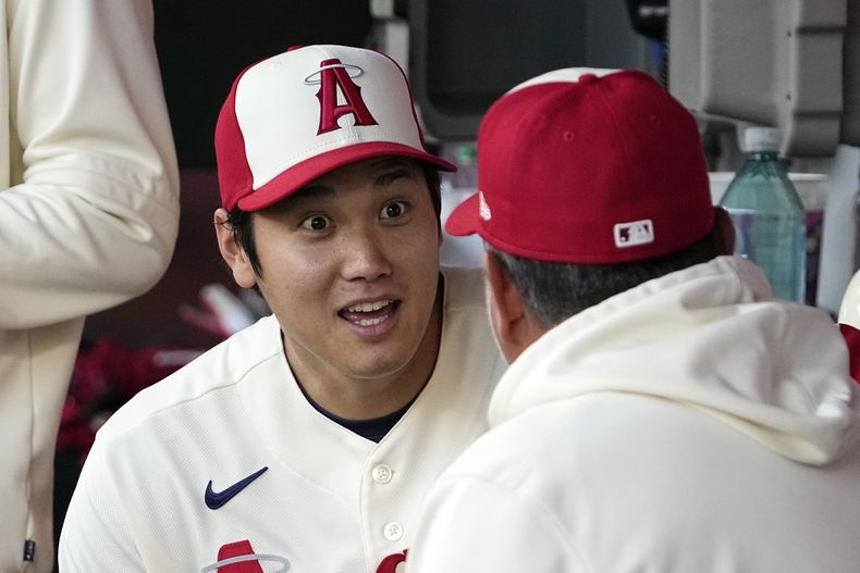 El japonés Shohei Ohtani, de los Angelinos de Los Ángeles, habla con el mexicano Benji Gil, coach de infield, antes del duelo del miércoles 26 de abril de 2023, ante los Atléticos de Oakland (AP Foto/Mark J. Terrill)
