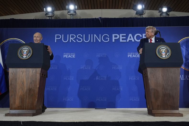 El presidente estadounidense Donald Trump, derecha, y su homólogo ruso Vladímir Putin hablan en una conferencia de prensa en la Base Conjunta Elmendorf-Richardson, el viernes 15 de agosto de 2025, en Alaska. El letrero del fondo dice: En busca de la paz. (AP Foto/Julia Demaree Nikhinson)