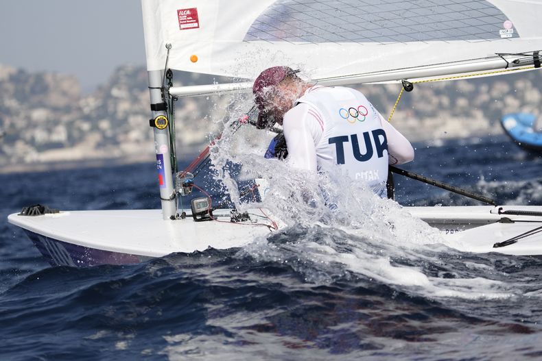 El turco Yigit Yalcin Citak se arroja agua para refrescarse durante una regata de dingui, en los Juegos Olímpicos, el jueves 1 de agosto de 2024, en Marsella (AP Foto/Jacquelyn Martin)