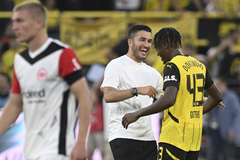 El técnico de Borussia Dortmund Nuri Sahin (centro) celebra con Jamie Gittens tras la victoria 2-0 ante Eintracht Frankfurt en la Bundesliga, el sábado 24 de agosto de 2024. (Bernd Thissen/dpa vía AP)