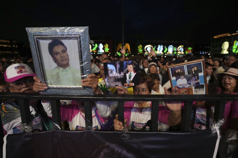 Fans de Juan Gabriel sostienen fotografías de él durante una proyección de uno de sus conciertos en el Zócalo, la plaza principal de la Ciudad de México, el domingo 22 de septiembre de 2024. (Foto AP/Fernando Llano)