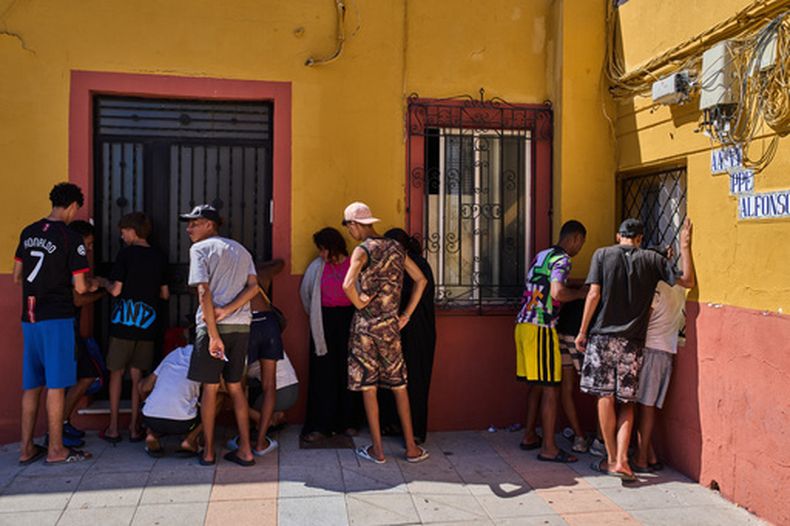 Varios migrantes, algunos de ellos menores no acompañados, que cruzaron desde Marruecos hacia España, escriben su información de contacto para dársela a una asociación vecinal en el enclave español de Ceuta, el martes 4 de agosto de 2026. (AP Foto/Bernat Armangue)
