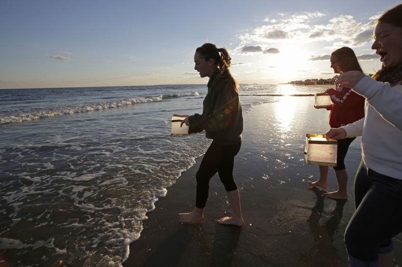 Unas mujeres se acercan al mar para colocar linternas con mensajes escritos en ellas durante una ceremonia para conmemorar un a&ntilde;o de que la tormenta Sandy azot&oacute; Nueva York, el domingo 27 de octubre de 2013. El aniversario se cumple el 29 de