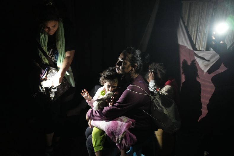La migrante venezolana Gabriela Villanueva sostiene a su hija mientras espera abordar un bote hacia Colombia en la isla caribeña de Gardi Sugdub, en Panamá, el lunes 24 de febrero de 2025, después de regresar del sur de México, donde perdieron las esperanzas de llegar a Estados Unidos en medio de la ofensiva del presidente Donald Trump contra la migración. (Foto AP/Matías Delacroix)