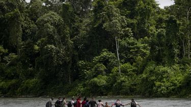 Los migrantes caminan de la mano mientras cruzan el río Tuquesa, cerca de Bajo Chiquito, Panamá, después de cruzar el Tapón del Darién desde Colombia en su camino hacia Norteamérica, el sábado 9 de noviembre de 2024. (Foto AP/Matías Delacroix)