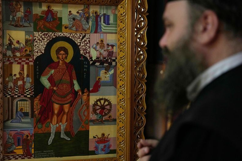 El padre Nikolaos Vlavianos al lado de un ícono de San Fanourios en la iglesia de San Fanourios en Atenas, Grecia, el 25 de agosto del 2026. (AP foto/Thanassis Stavrakis)