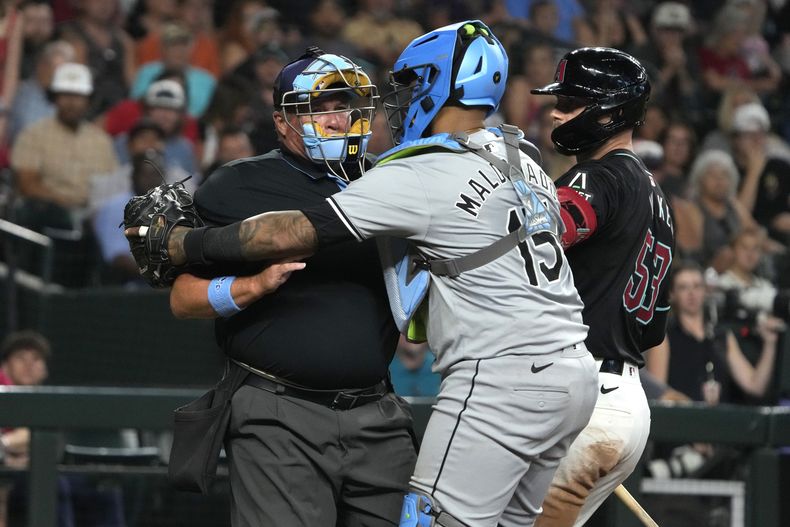 El receptor de los Medias Blancas de Chicago, Martin Maldonado (15), sostiene al umpire Marvin Hudson, después de que éste fuera golpeado por un faul durante la sexta entrada del juego de béisbol en contra de los Diamondbacks de Arizona, el domingo 16 de junio de 2024, en Phoenix. Hudson dejó el partido y no regresó. (AP Foto/Rick Scuteri)