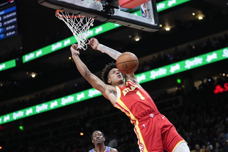 El alero de los Hawks de Atlanta, Jalen Johnson (1), anota mientras el alero del Thunder de Oklahoma City, Jalen Williams (8), observa durante la primera mitad de un partido de baloncesto de la NBA, el miércoles 3 de enero de 2024, en Atlanta. (AP Foto/John Bazemore)