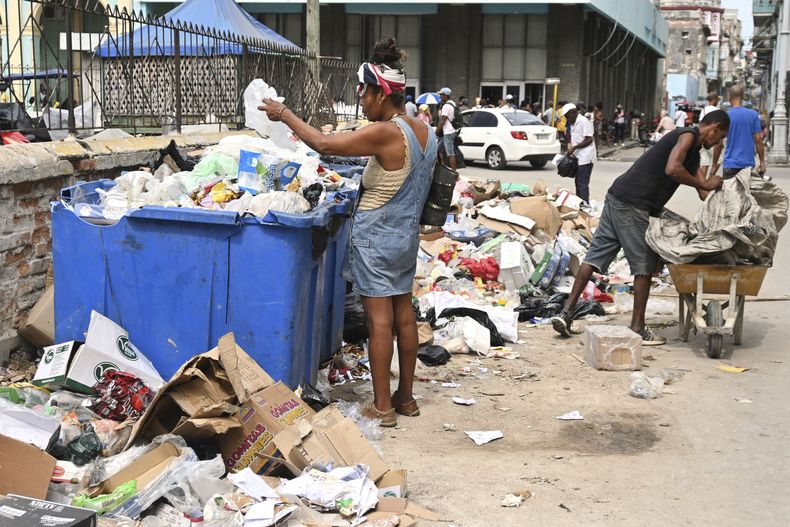 Una mujer busca en un contenedor de basura artículos útiles, en La Habana, Cuba, el martes 15 de julio de 2025. (Foto AP/Jorge Luis Baños)