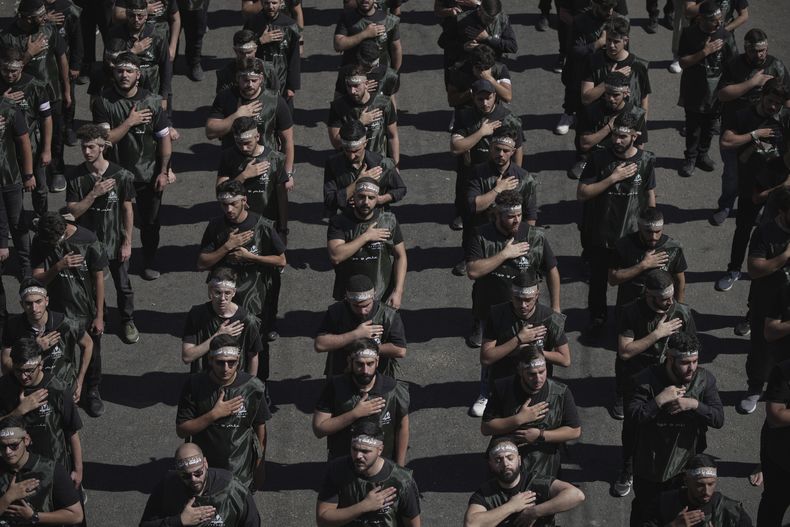 Partidarios de Hezbollah se llevan la mano al pecho al marchar durante el Ashoura, la conmemoración musulmana chií por la muerte en el siglo VII del imán Hussein, nieto del profeta Mahoma, en la batalla de Kerbala, durante celebraciones en los suburbios sur de Beirut, Líbano, el 6 de julio de 2025. (AP Foto/Hassan Ammar)