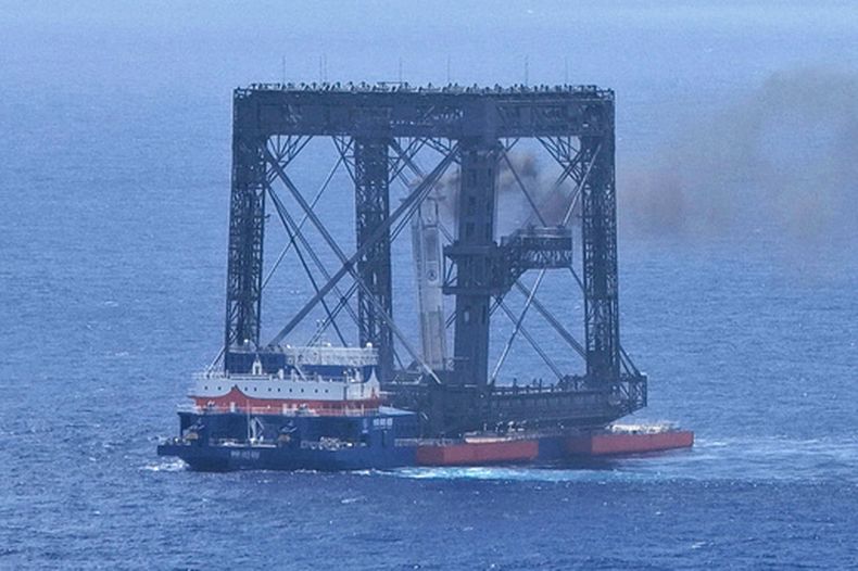 En esta fotografía difundida por la agencia de noticias Xinhua, una imagen tomada con un dron muestra la captura exitosa de la primera etapa del cohete portador Larga Marcha-10B --que había regresado a una plataforma marítima-- mediante un sistema de captura con red, el viernes 10 de julio de 2026, cerca de Wenchang, en la provincia de Hainan, en el sur de China. (Xing Guangli/Agencia de Noticias Xinhua vía AP)