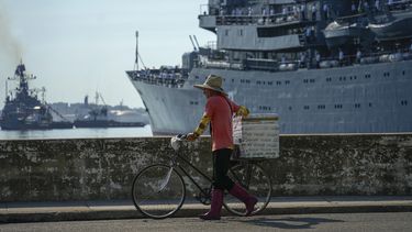 Un vendedor ambulante camina con su bicicleta junto al buque escuela ruso Smolny cuando llega para una visita de trabajo, en la bahía de La Habana, Cuba, el sábado 27 de julio de 2024. (Foto AP/Ramón Espinosa)