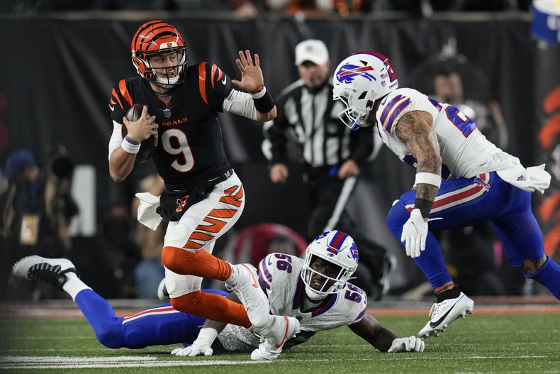 Joe Burrow (9), quarterback de los Bengals de Cincinnati, corre con el balón después de dejar tendido a Leonard Floyd (56) y el safety Taylor Rapp, de los Bills de Buffalo, intenta derribarlo durante la segunda mitad del juego de la NFL, el domingo 5 de noviembre de 2023, en Cincinnati. (AP Foto/Carolyn Kaster)