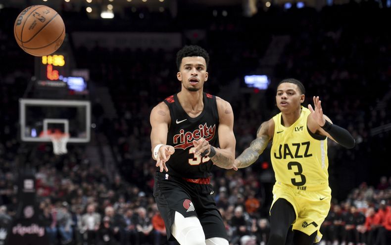 Toumani Camara, alero de los Trail Blazers de Portland, envía un pase frente a Keyonte George, del Jazz de Utah, en el encuentro del miércoles 22 de noviembre de 2023 (AP Foto/Steve Dykes)