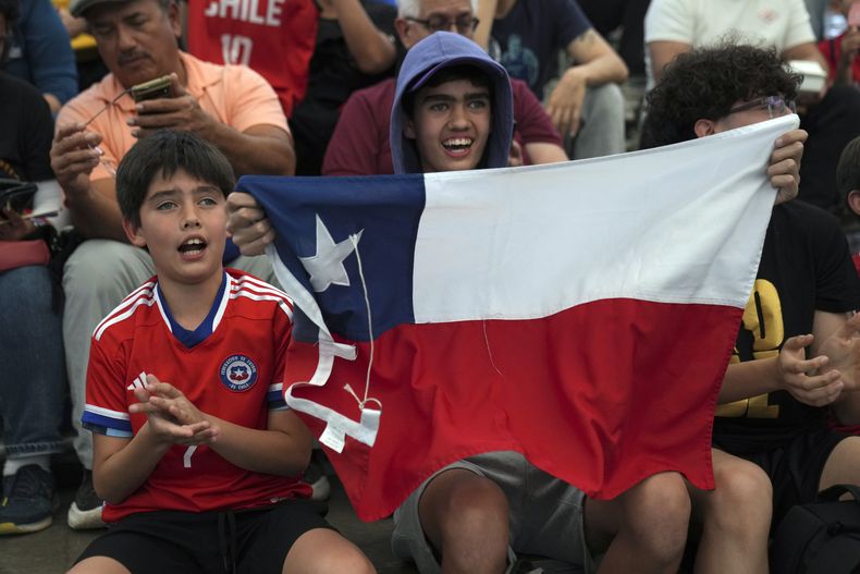 Aficionados sostienen una bandera de Chile durante las semifinales del baloncesto femenino 3x3 en los Juegos Panamericanos en Santiago, Chile, el lunes 23 de octubre de 2023. (AP Foto/MDolores Ochoa)