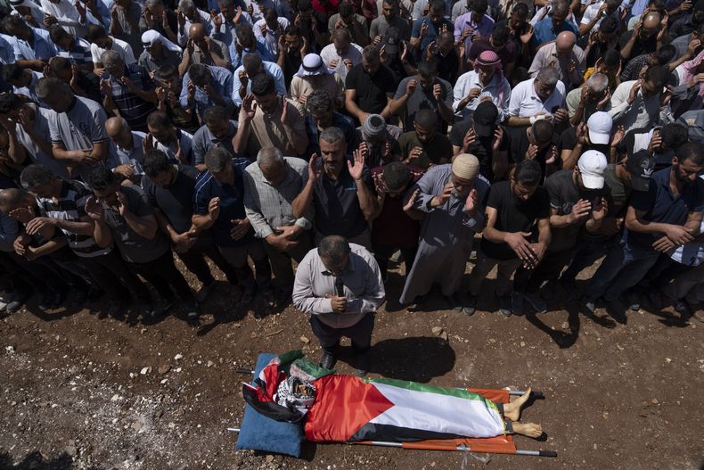Dolientes realizan oraciones cerca del cadáver del profesor de inglés palestino Abdulrahim Ghannam, de 36 años, en su funeral en el poblado cisjordano de Aqaba, el viernes 1 de septiembre de 2023. (AP Foto/Nasser Nasser)