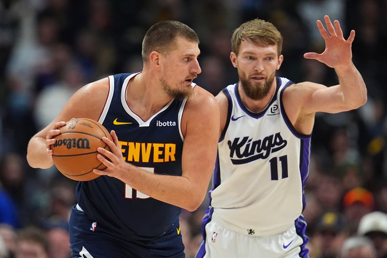 Nikola Jokic, izquierda, de los Nuggets de Denver, busca pasar el balón mientras Domantas Sabonis, de los Kings de Sacramento, defiende durante la primera mitad del juego de baloncesto de la NBA, el lunes 3 de noviembre de 2025, en Denver. (AP Foto/David Zalubowski)