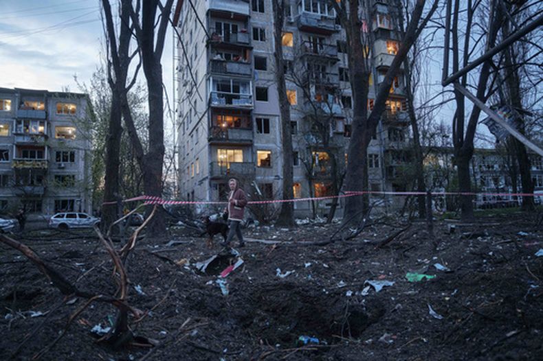 Una mujer pasea con un perro entre los escombros de una casa dañada en un ataque ruso a una zona residencial en Kiev, Ucrania, el 16 de abril de 2026. (AP Foto/Evgeniy Maloletka)