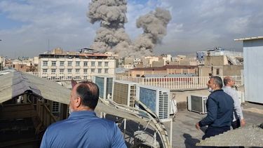 Varias personas observan mientras una columna de humo señala el lugar donde se produjo una explosión en Teherán, Irán, el 28 de febrero de 2026. (AP Foto)