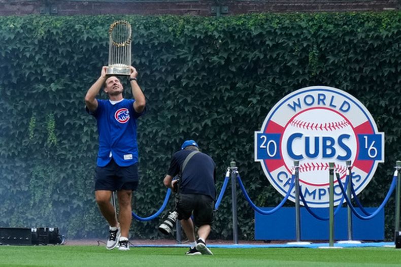 El ex primera base de los Cachorros de Chicago, Anthony Rizzo, sostiene el trofeo de campeonato de la Serie Mundial de 2016 mientras camina por el campo antes de un partido de béisbol entre los Mellizos de Minnesota y los Cachorros de Chicago en Chicago, el sábado 18 de julio de 2026. (Foto AP/Nam Y. Huh)