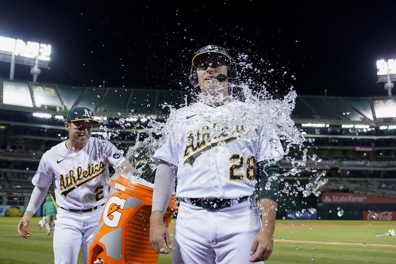 Nick Allen (izquierda) de los Atléticos de Oakland, arroja agua helada a Jonah Brice, tras la victoria sobre los Bravos de Atlanta, el martes 30 de mayo de 2023 (AP Foto/Godofredo A. Vásquez)