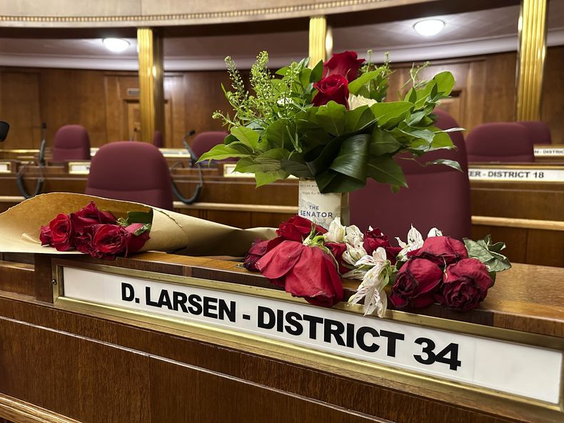 Flores en el escaño senatorial del fallecido senador estatal de Dakota del Norte Doug Larsen, el 6 de octubre del 2023 en Bismarck, Dakota del Norte. (AP foto/Jack Dura)