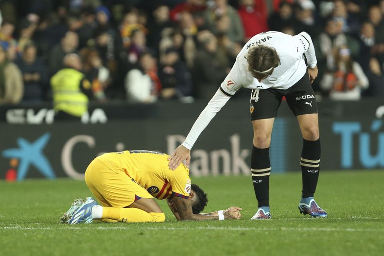 Yarek Gasiorowski, del Valencia, trata de consolar al brasileño Raphinha, del Barcelona, tras el empate en un partido de La Liga, el sábado 16 de diciembre de 2023 (AP Foto/Alberto Sáiz)