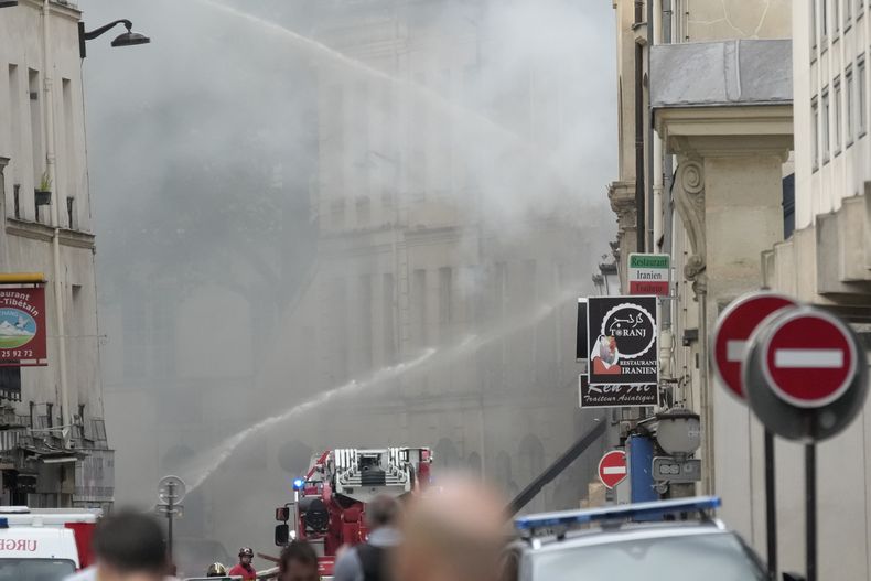 Bomberos combaten con un camión hidrante un incendio en la margen izquierda del Sena, París, miércoles 21 de junio de 2023. Vecinos dijeron a la prensa local que una fuerte explosión precedió el incendio y parte de un edificio se derrumbó. (AP Foto/Christophe Ena)