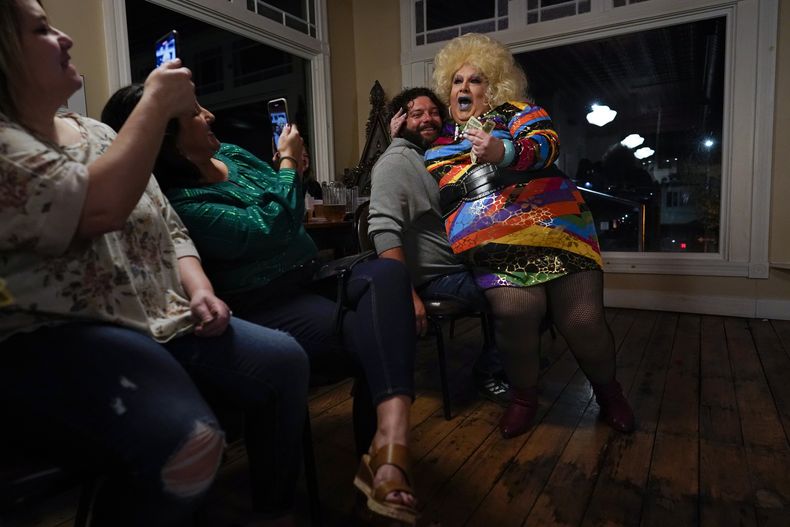 La drag queen Alexus Daniels interpreta Heart of Glass de Blondie sentada en regazo de un integrante de la audiencia que sonrie y dio su consentimiento mientras otros toman fotografías durante el espectáculo Daniels Family Values en el Heritage Restaurant en Shamokin, Pensilvannia, el 16 de abril de 2022. Daniels, la matriarca de una familia dra, es hija de un miero de carbó y una trabajadora textil que nació con un espíritu femenino. Trabaja en un hospital local. (Foto AP/Carolyn Kaster)