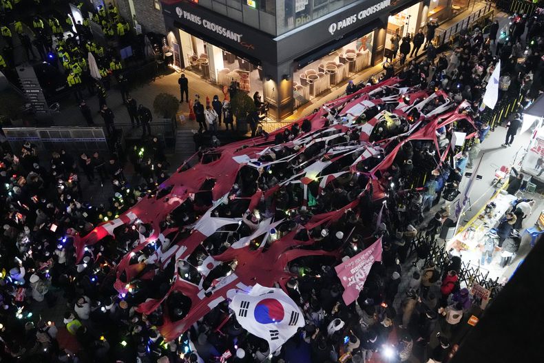 Manifestantes desgarran un estandarte que representa el Partido del Poder Popular (PPP) durante una marcha para exigir que el presidente surcoreano Yoon Suk Yeol enfrente juicio político, frente a la sede del PPP en Seúl, Corea del Sur, el lunes 9 de diciembre de 2024. (AP Foto/Ahnn Young-joon)