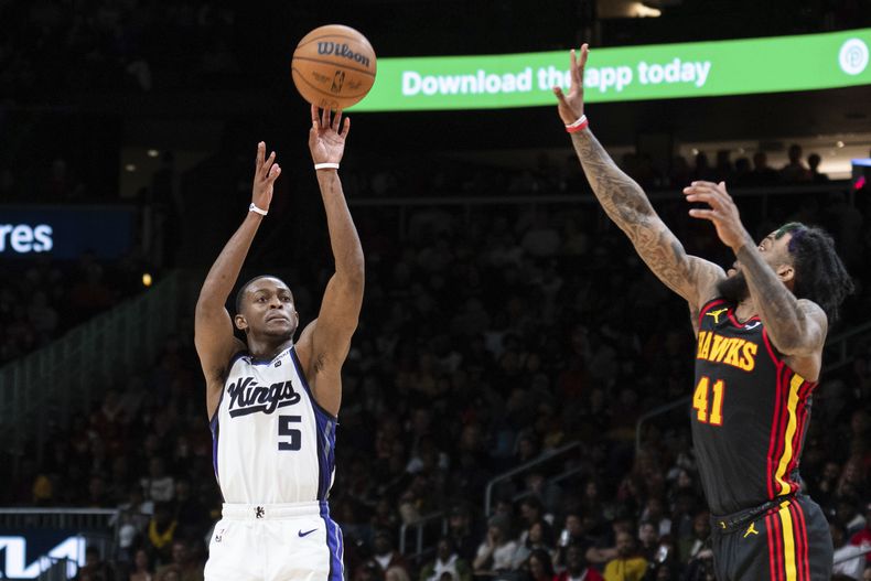 DeAaron Fox, de los Kings de Sacramento, dispara frente a Saddiq Bey, de los Hawks de Atlanta, en el partido del viernes 29 de diciembre de 2023 (AP Foto/Hakim Wright Sr.)