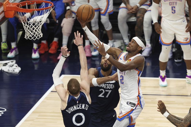 El base del Thunder de Oklahoma City Shai Gilgeous-Alexander salta para anotar frente a Donte DiVincenzo y Rudy Gobert de los Timberwolves de Minnesota en el juego 4 de las Finales de la Conferencia Oeste el lunes 26 de mayo del 2025. (AP Foto/Matt Krohn)