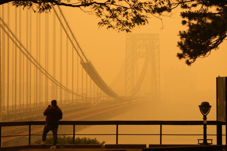 Un hombre habla por teléfono mientras observa la bruma en el puente George Washington, el miércoles 7 de junio de 2023, desde Fort Lee, Nueva Jersey. (AP Foto/Seth Wenig)