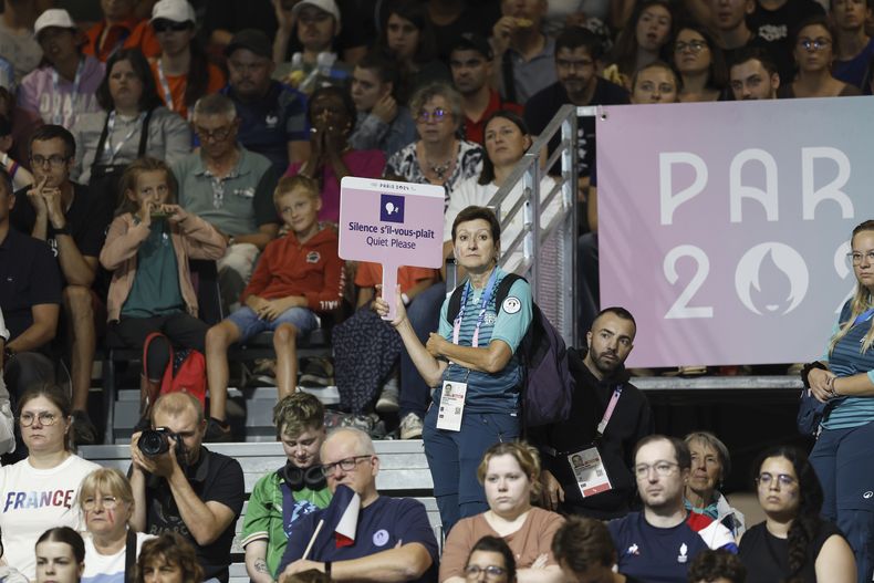 Una voluntaria de los Juegos Paralímpicos de París sostiene un cartel que pide al público guardar silencio durante un partido de golbol entre Estados Unidos y Francia, el sábado 31 de agosto de 2024 (AP Foto/Felix Scheyer)