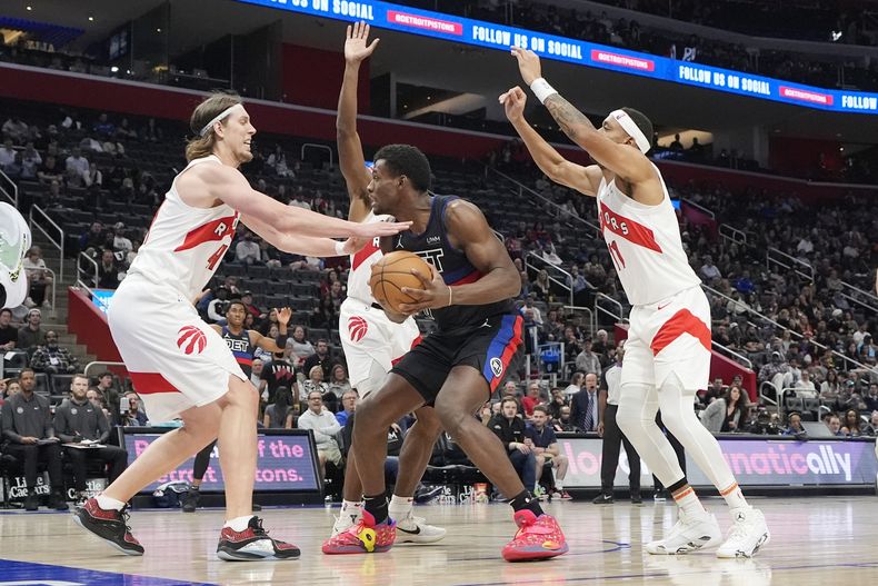El centro de los Pistons de Detroit Jalen Duren (0) es marcado por el alero de los Raptors de Toronto Kelly Olynyk (izquierda) y el alero Bruce Brown (1) durante la segunda mitad del juego de baloncesto de la NBA, el miércoles 13 de marzo de 2024, en Detroit. (AP Foto/Carlos Osorio)