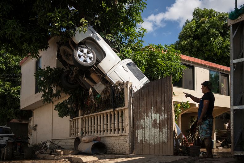Una camioneta sobre la cerca de una residencia después de intensas lluvias e inundaciones, el domingo 12 de octubre de 2025, en Poza Rica, Veracruz, México. (AP Foto/Félix Márquez)